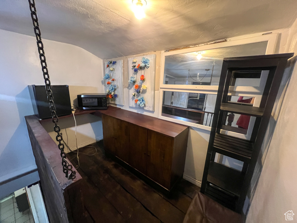 Kitchen featuring dark hardwood / wood-style floors, vaulted ceiling, and a textured ceiling