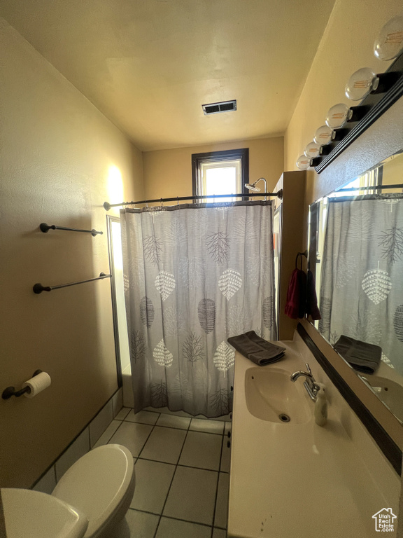 Full bathroom featuring tile patterned flooring, sink, toilet, and shower / bath combo with shower curtain