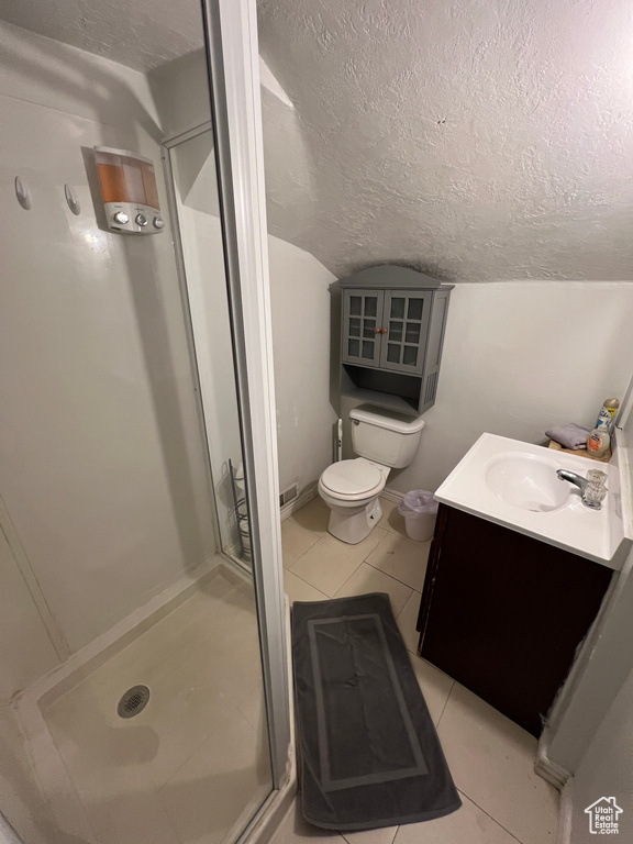 Bathroom featuring vanity, a textured ceiling, a shower with shower door, tile patterned floors, and toilet