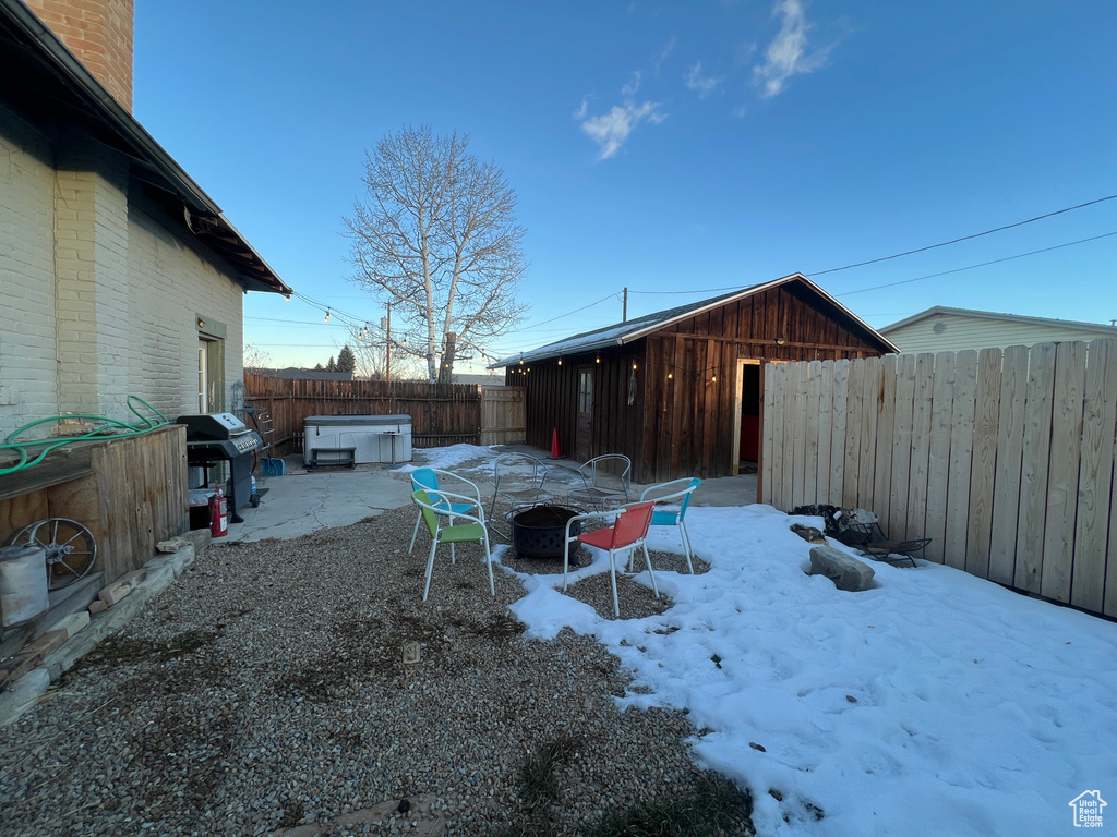 Yard layered in snow featuring a hot tub and an outdoor fire pit