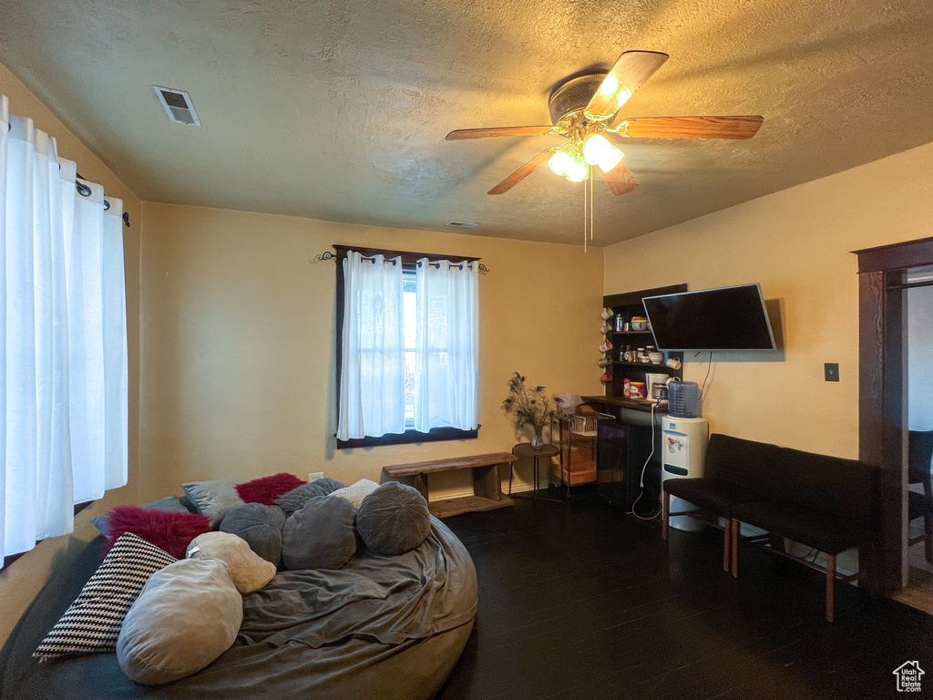 Bedroom with ceiling fan, dark hardwood / wood-style flooring, and a textured ceiling