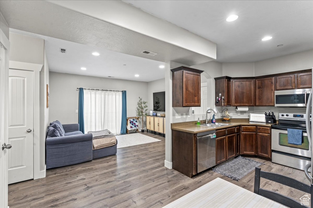 Kitchen with sink, dark brown cabinets, stainless steel appliances, and light wood-type flooring