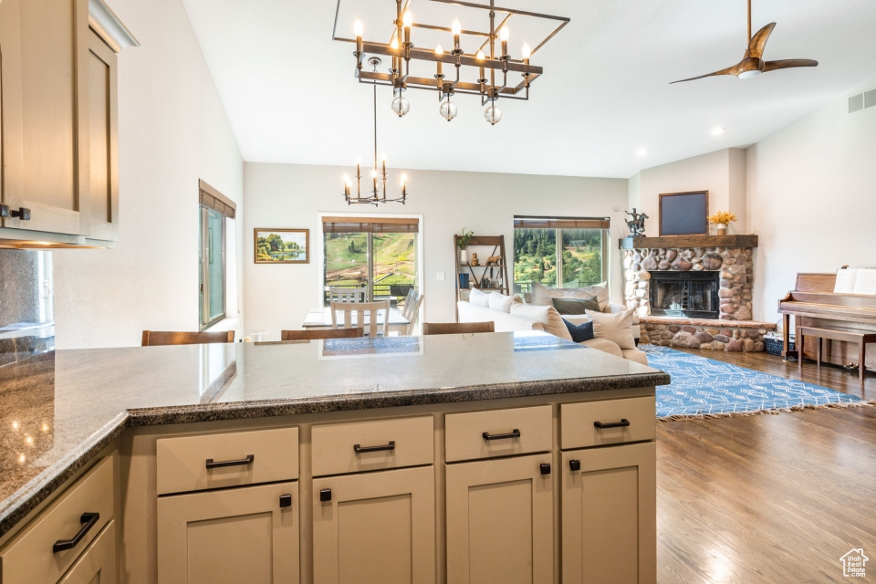 Kitchen with pendant lighting, lofted ceiling, a fireplace, and light hardwood / wood-style flooring