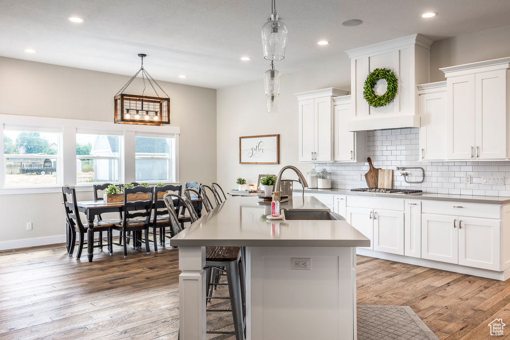 Kitchen with a center island with sink, white cabinetry, and pendant lighting