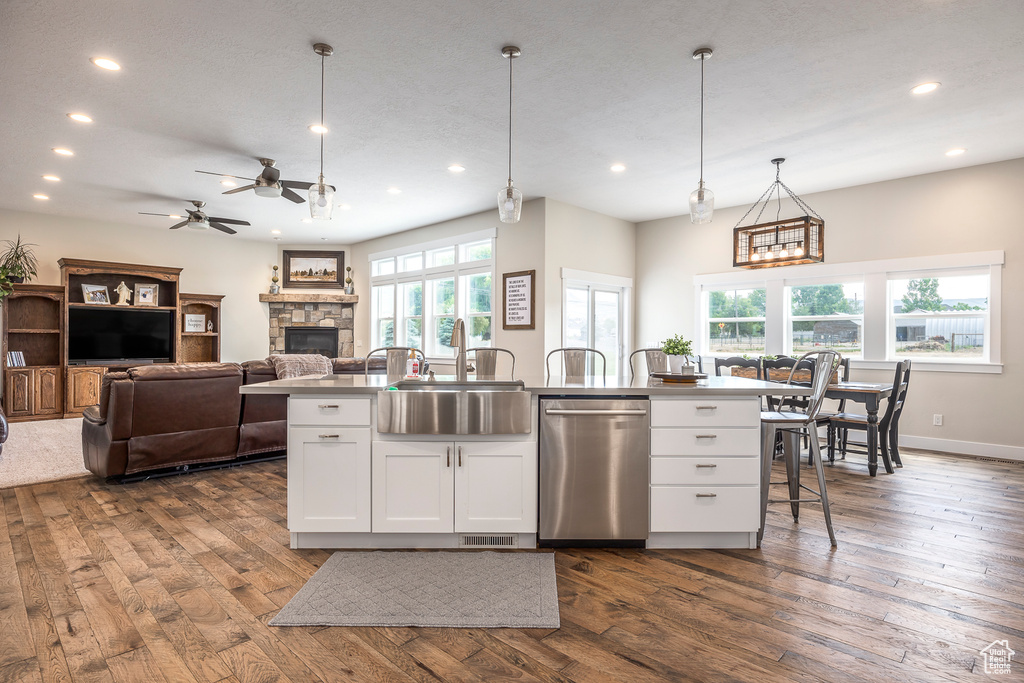 Kitchen featuring sink, dishwasher, a kitchen island with sink, and white cabinets