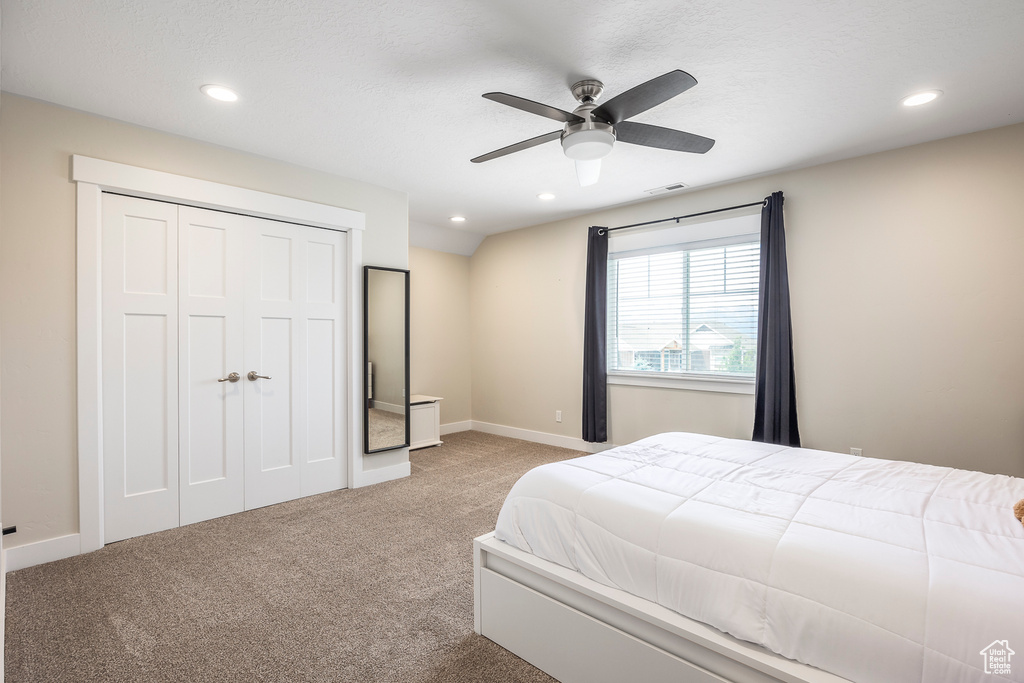 Carpeted bedroom with a closet and ceiling fan