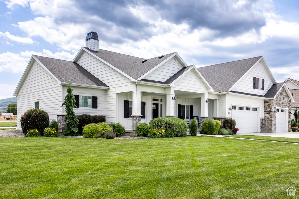 View of front of house featuring a garage, a front yard, and a porch