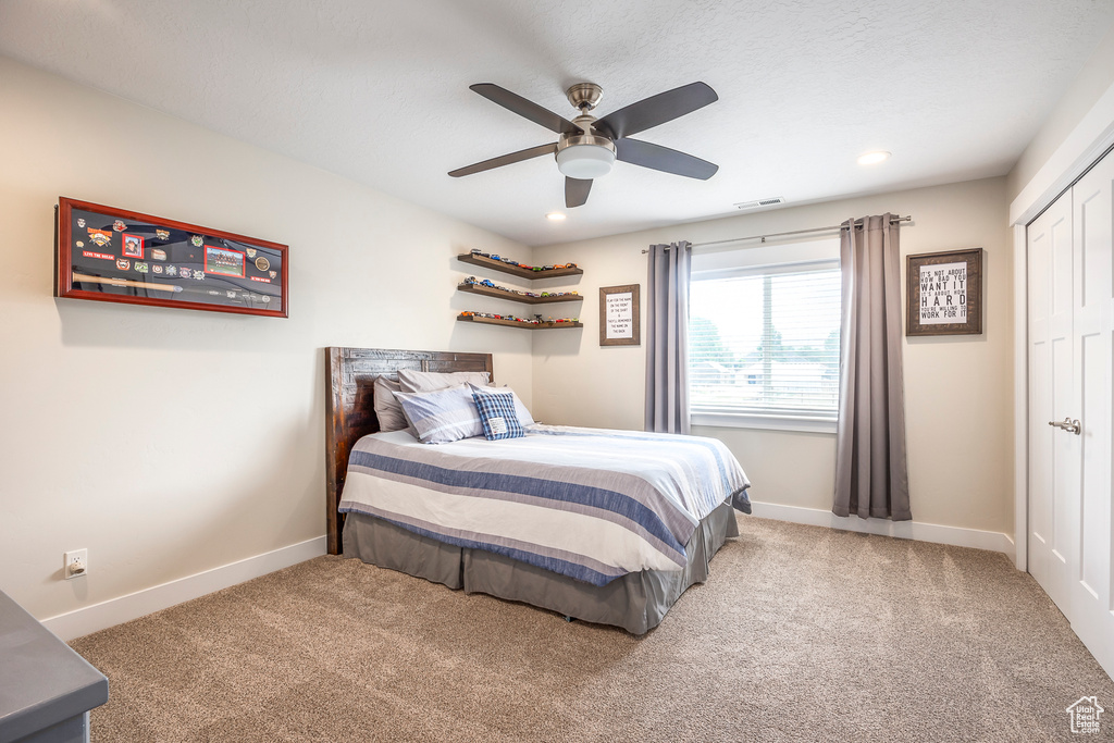 Carpeted bedroom featuring a closet and ceiling fan