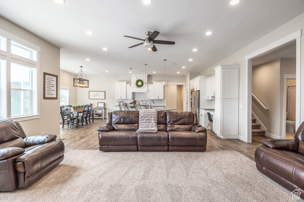 Living room with ceiling fan, sink, and light wood-type flooring