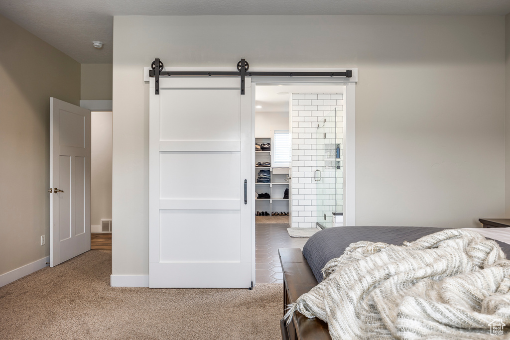 Bedroom featuring a barn door and carpet flooring