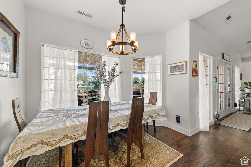 Dining area featuring a notable chandelier, dark wood-type flooring, french doors, and vaulted ceiling