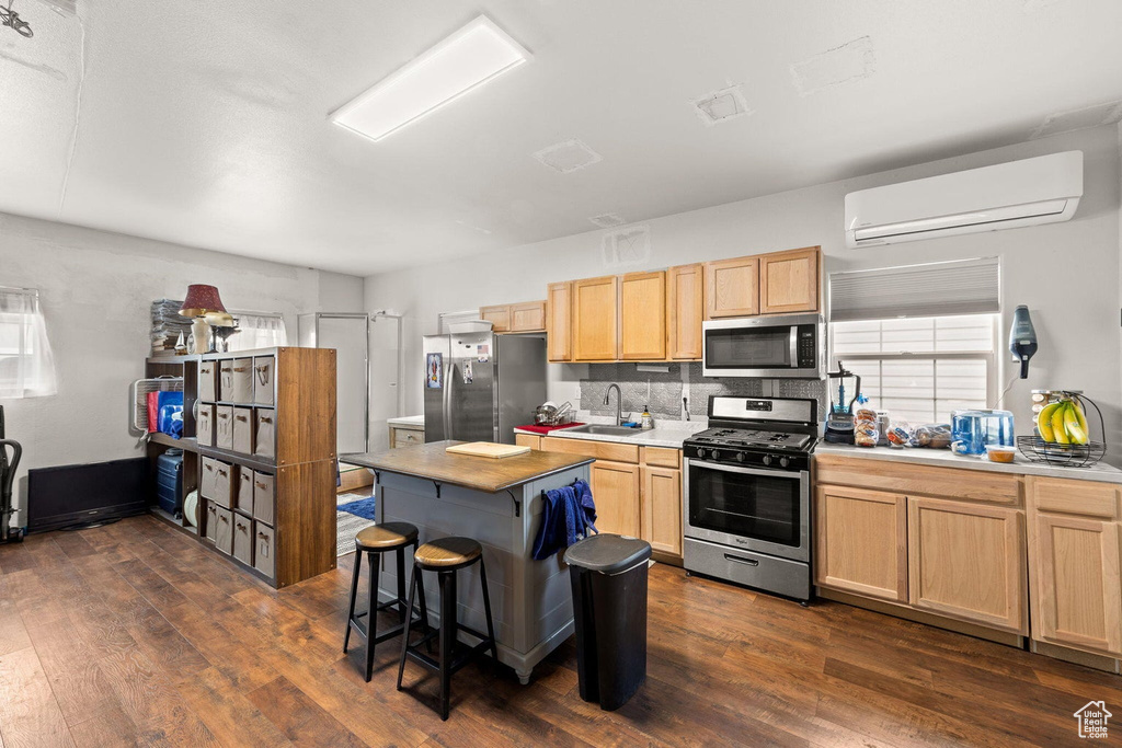 Kitchen featuring sink, backsplash, a wall unit AC, stainless steel appliances, and dark hardwood / wood-style floors