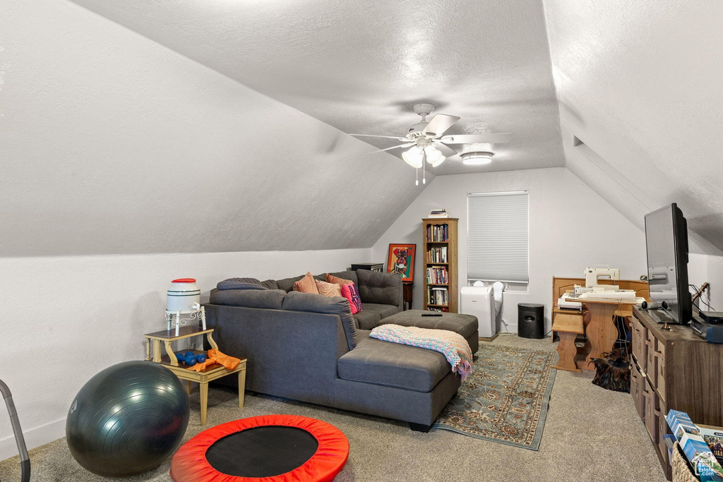 Living room featuring light carpet, ceiling fan, vaulted ceiling, and a textured ceiling