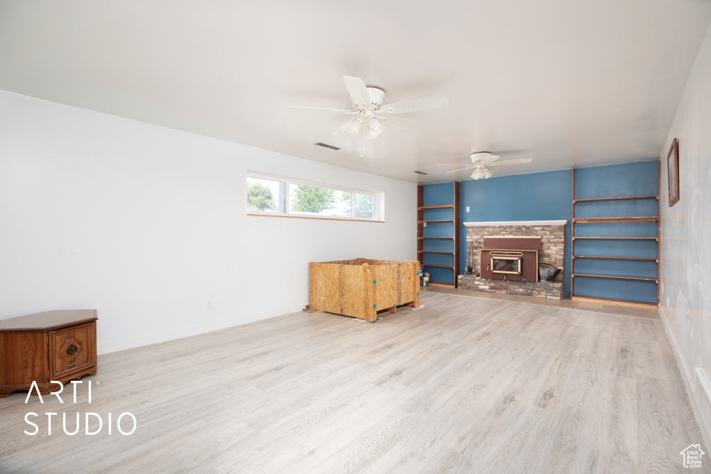 Living room featuring a fireplace, light hardwood / wood-style flooring, built in features, and ceiling fan