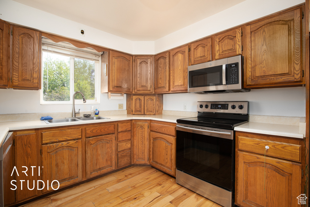 Kitchen with appliances with stainless steel finishes, sink, and light wood-type flooring