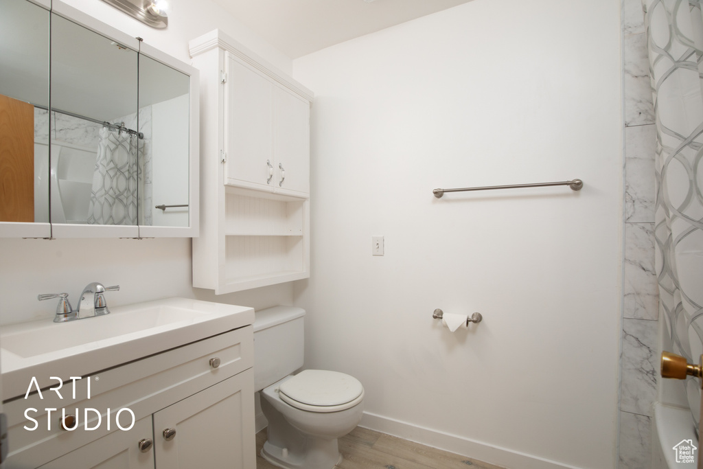 Bathroom featuring walk in shower, vanity, toilet, and hardwood / wood-style flooring