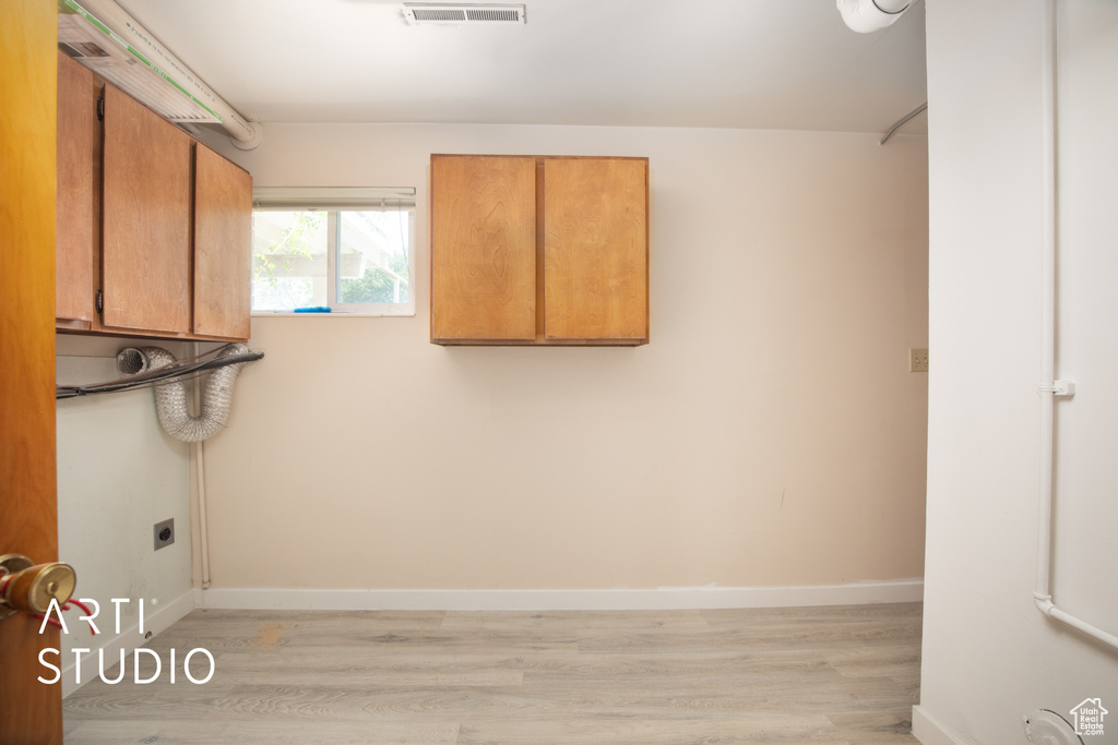 Laundry room featuring cabinets, electric dryer hookup, and light hardwood / wood-style floors