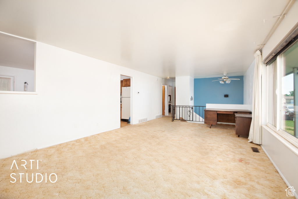 Unfurnished living room with light colored carpet and ceiling fan