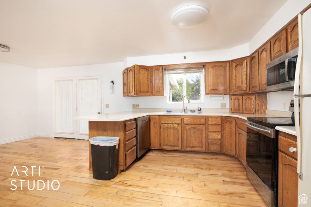 Kitchen with sink, stainless steel appliances, kitchen peninsula, and light wood-type flooring