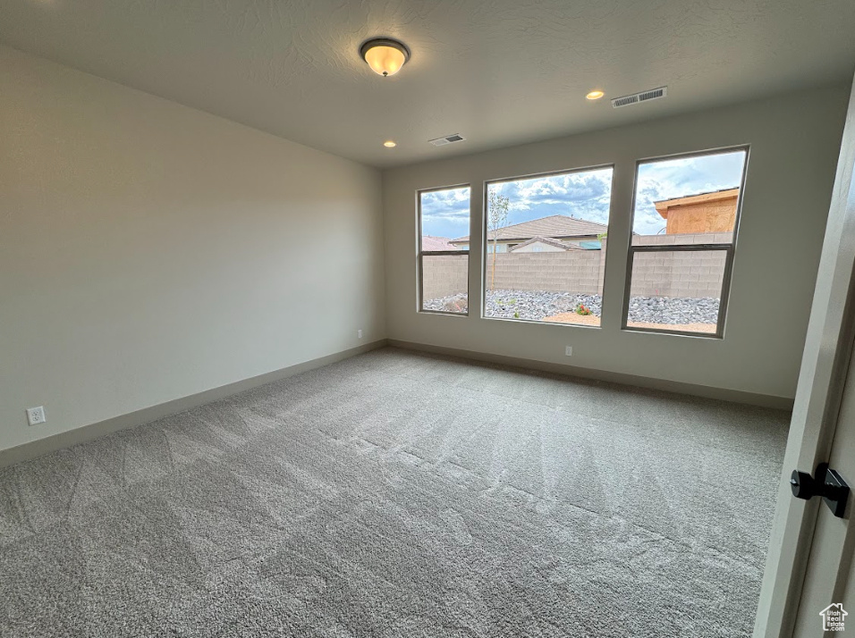 Unfurnished room featuring visible vents, carpet flooring, and baseboards