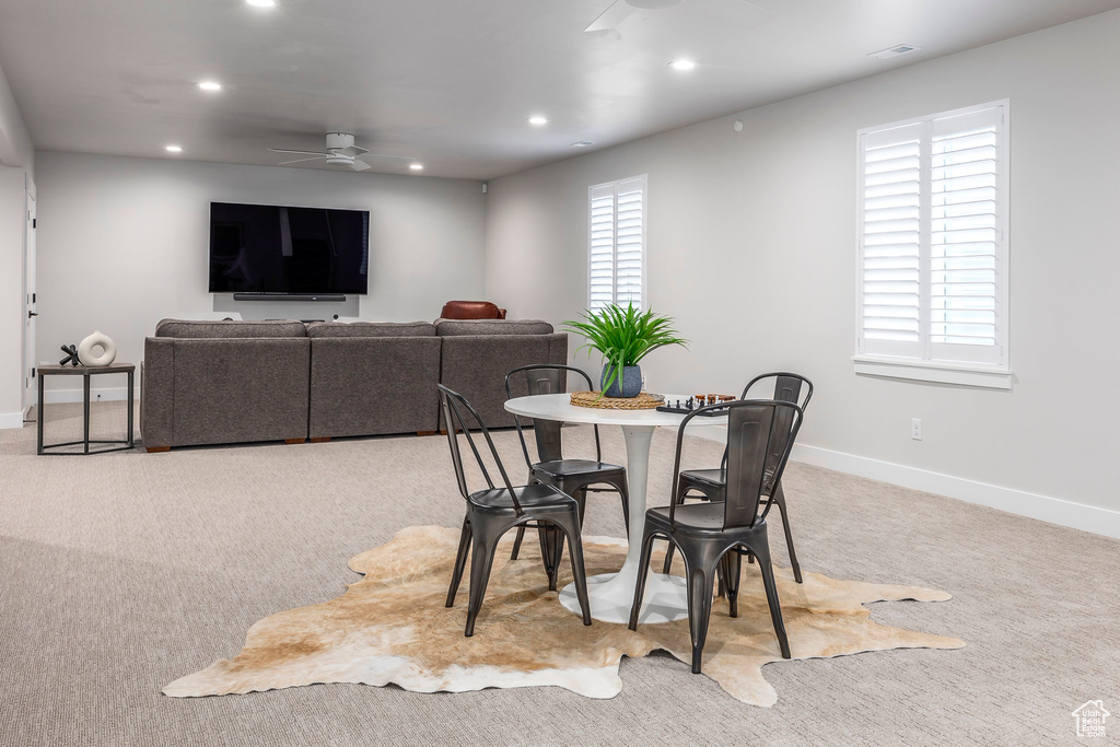Carpeted dining room with a healthy amount of sunlight and ceiling fan