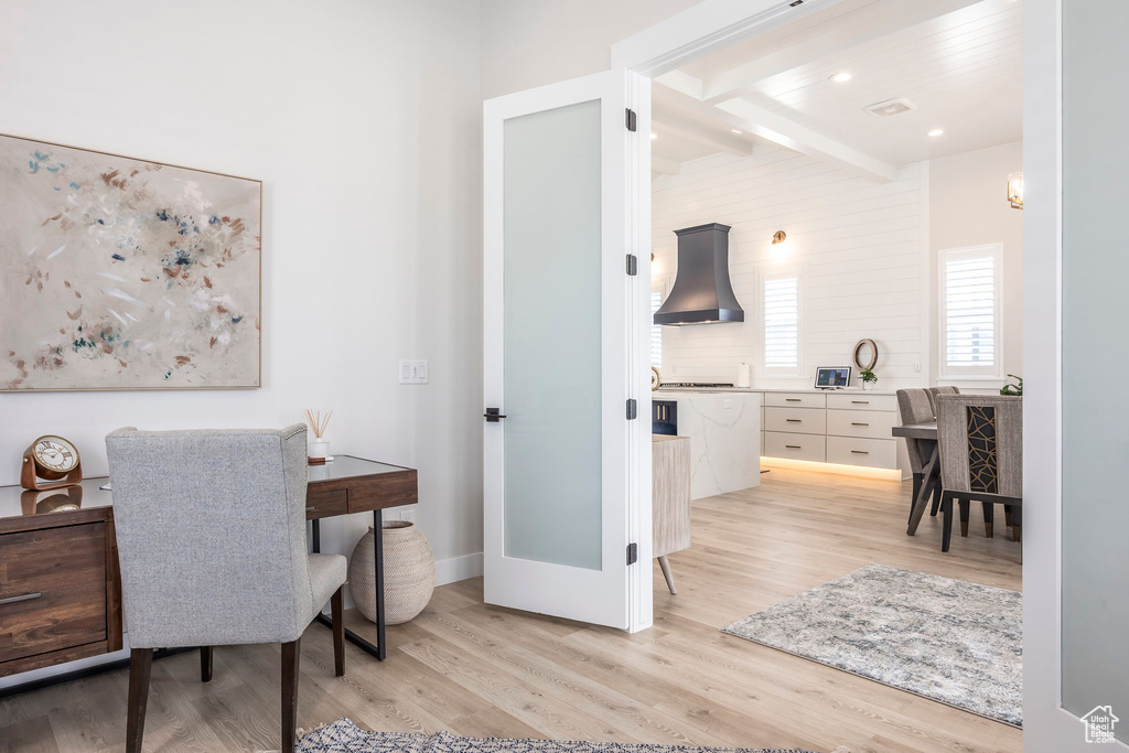 Office space with beam ceiling and light hardwood / wood-style floors