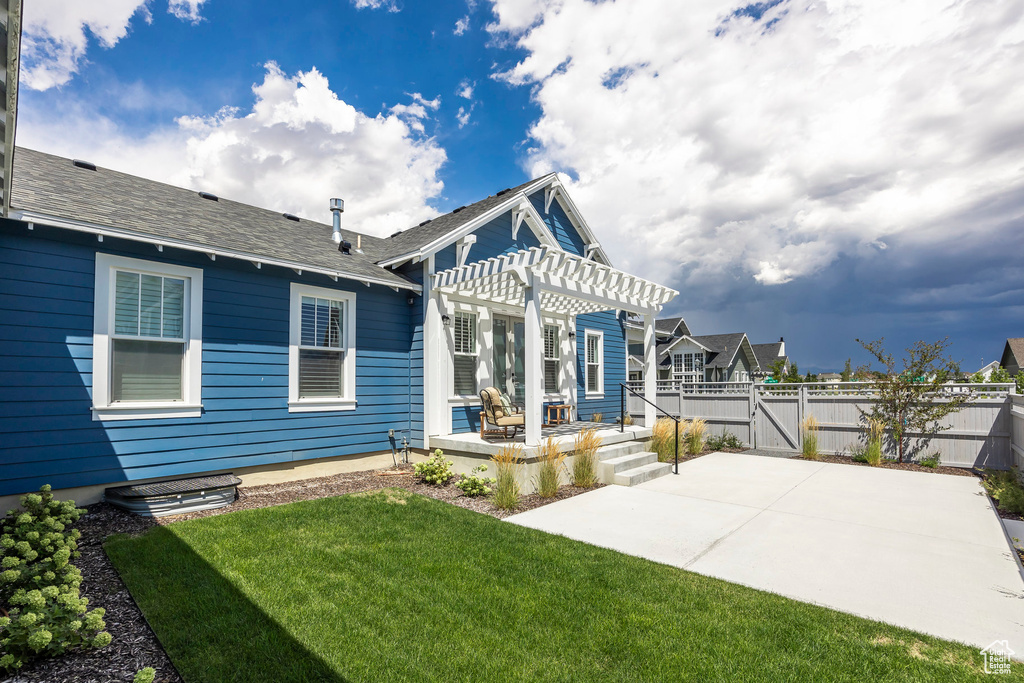 Back of property featuring a pergola, a patio area, and a lawn