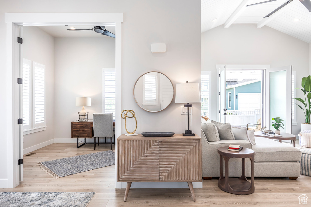 Living room with beamed ceiling, ceiling fan, a wealth of natural light, and light wood-type flooring