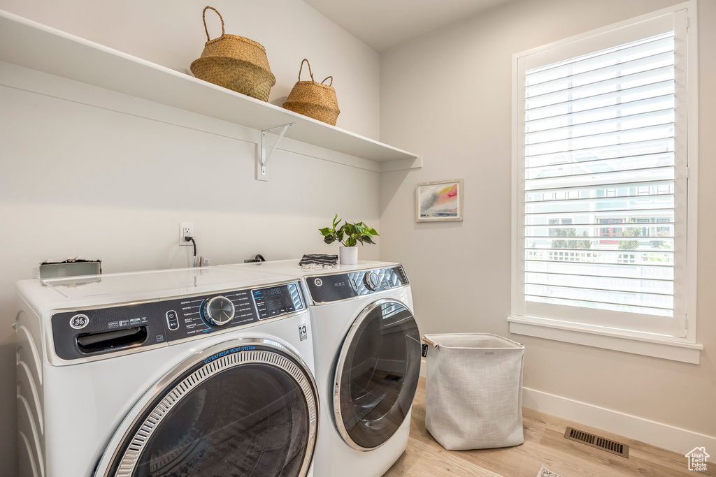 Laundry area featuring a wealth of natural light, wood-type flooring, and independent washer and dryer