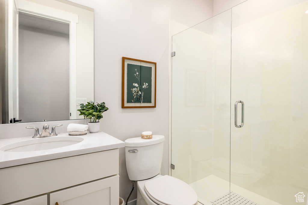 Bathroom with a shower with door, vanity, and toilet
