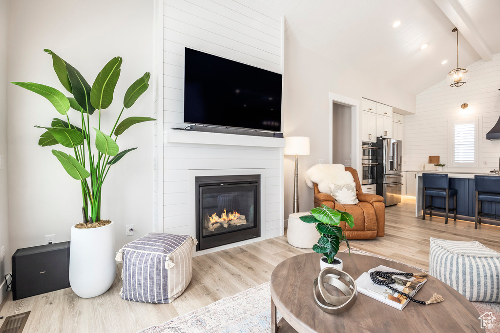 Living room featuring beam ceiling, high vaulted ceiling, and light hardwood / wood-style flooring
