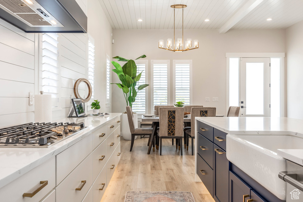 Kitchen featuring white cabinetry, beam ceiling, exhaust hood, and stainless steel gas stovetop
