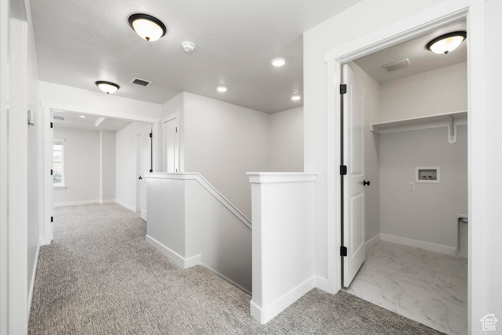 Hallway featuring light colored carpet