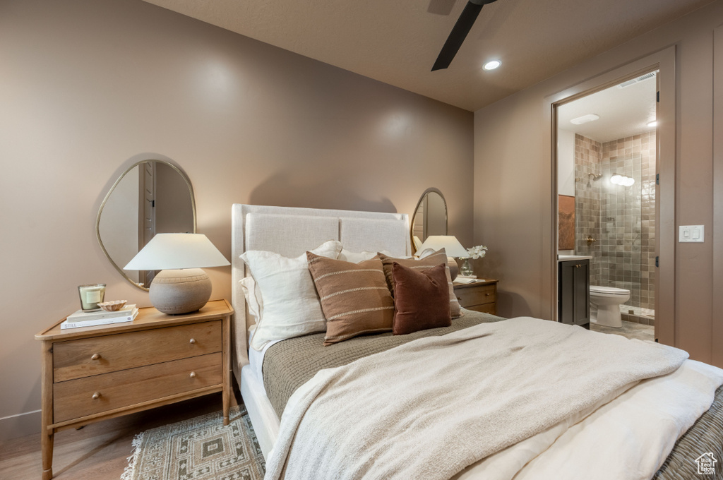 Bedroom with ensuite bath, wood finished floors, baseboards, and a ceiling fan