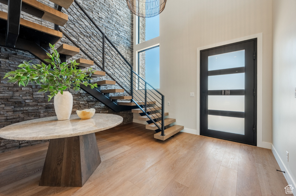 Foyer featuring stairs, wood finished floors, a towering ceiling, and baseboards