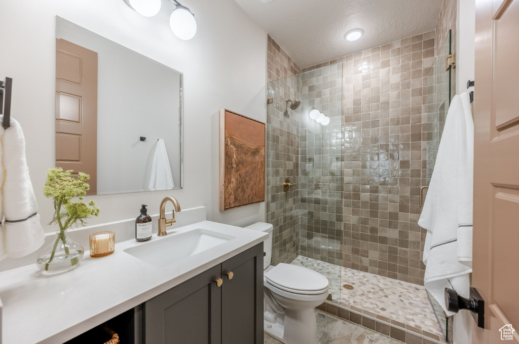 Full bath featuring a tile shower, toilet, and vanity