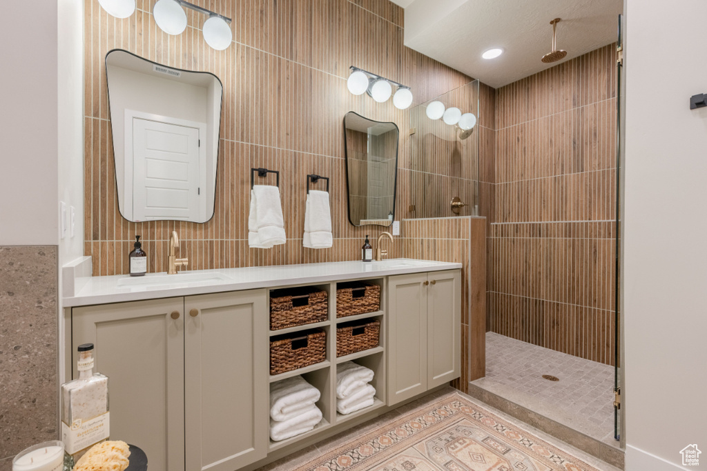 Full bathroom featuring double vanity, walk in shower, and tile walls