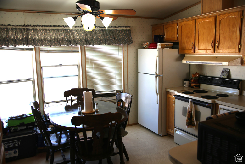 Kitchen featuring ceiling fan, white appliances, ornamental molding, and vaulted ceiling