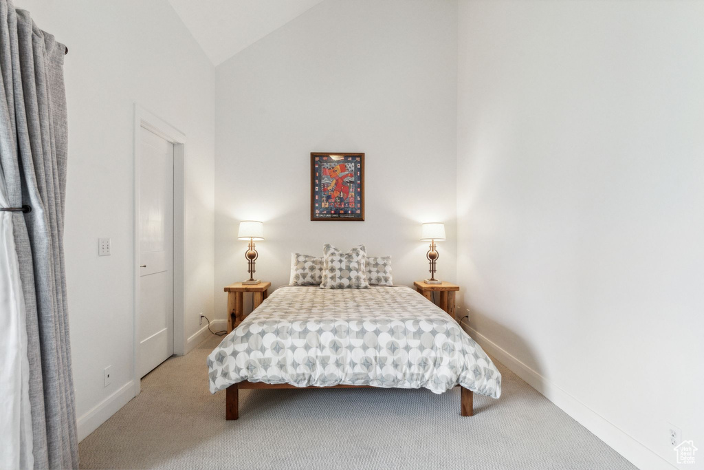 Carpeted bedroom with vaulted ceiling and baseboards