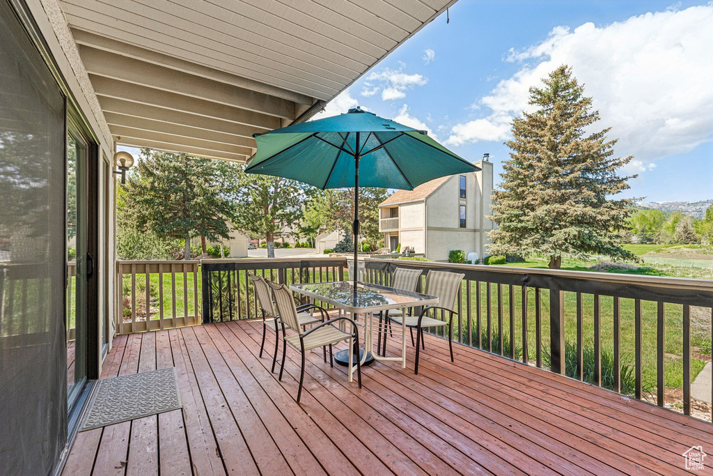 Wooden terrace with outdoor dining space and a yard