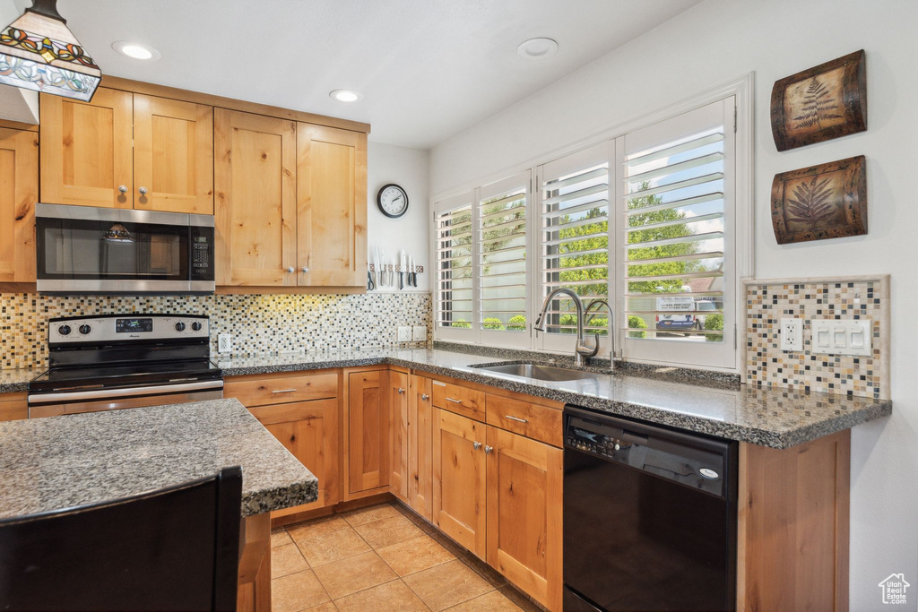 Kitchen with stainless steel appliances, a sink, backsplash, dark stone counters, and recessed lighting