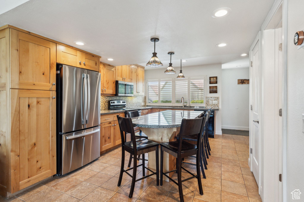 Kitchen with stainless steel appliances, recessed lighting, backsplash, dark stone countertops, and a sink