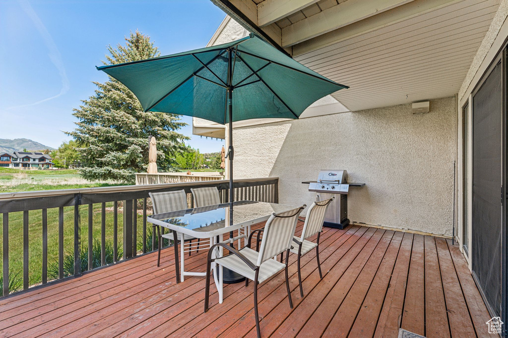 Wooden terrace with outdoor dining space, area for grilling, and a lawn