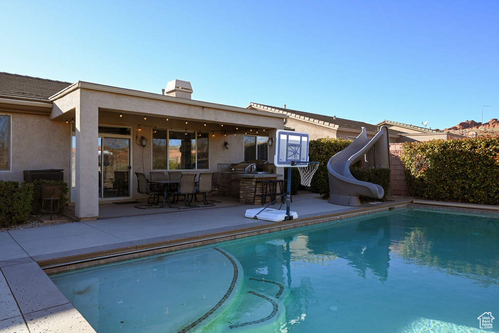 View of pool featuring area for grilling, a patio, and a water slide