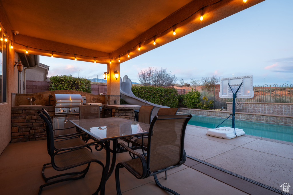 View of patio / terrace with outdoor dining space, an outdoor kitchen, a fenced backyard, and a fenced in pool
