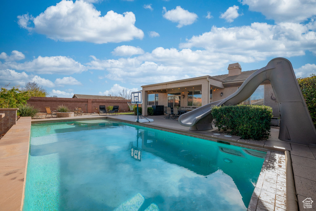 View of pool with a fenced in pool, fence, a water slide, and a patio