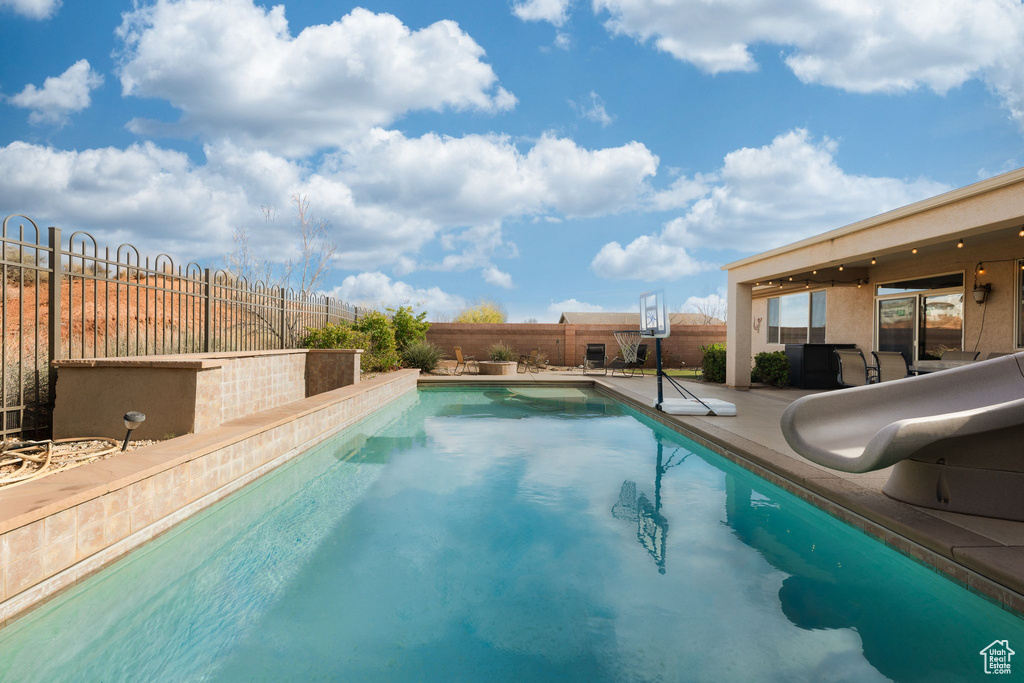 View of pool with a fenced in pool, a patio area, a water slide, and a fenced backyard