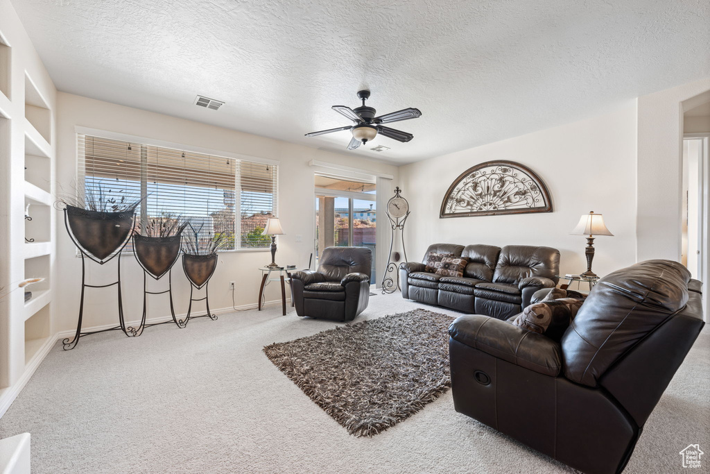 Living room with ceiling fan, carpet, and a textured ceiling