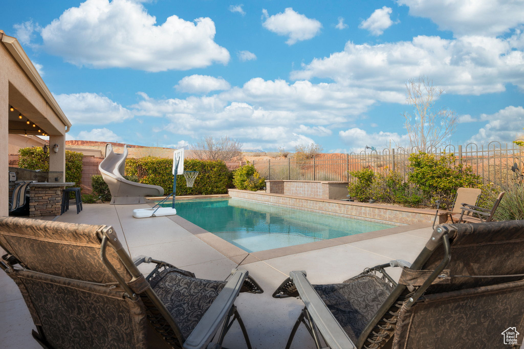 View of swimming pool featuring a fenced in pool, outdoor dry bar, a patio area, a water slide, and a fenced backyard