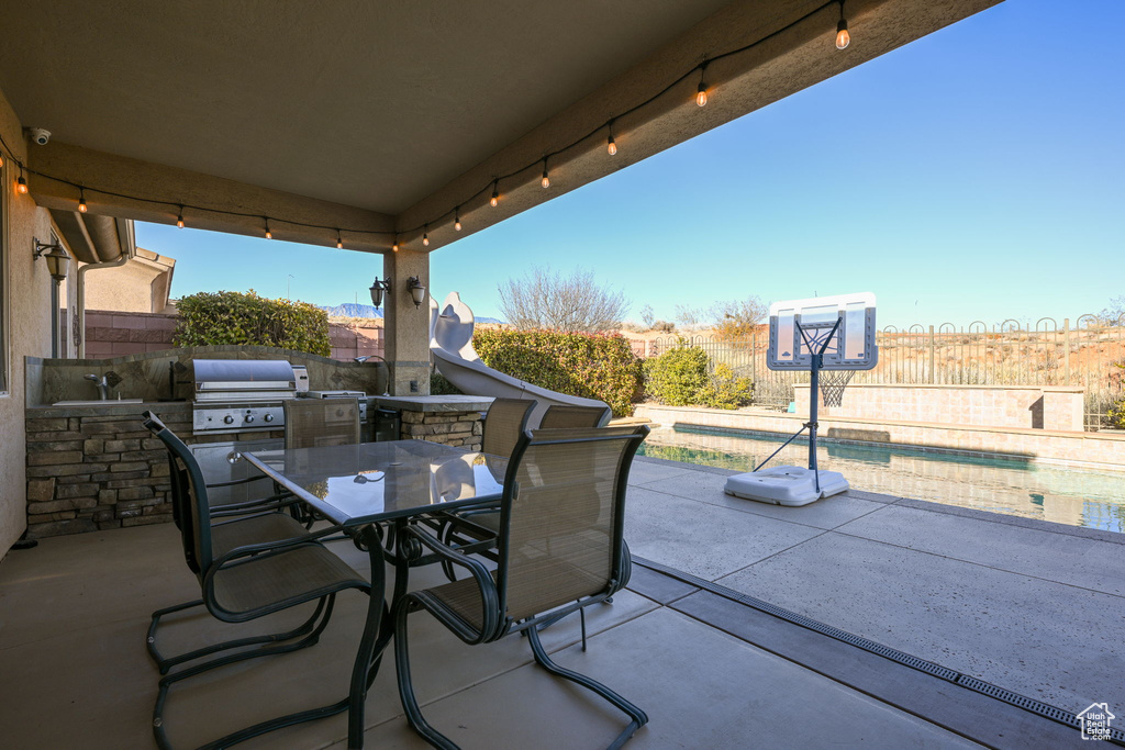 View of patio featuring area for grilling and a fenced in pool